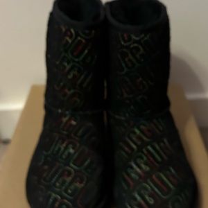 Black boots with Red, green and yellow stitching spelling UGG all over them.